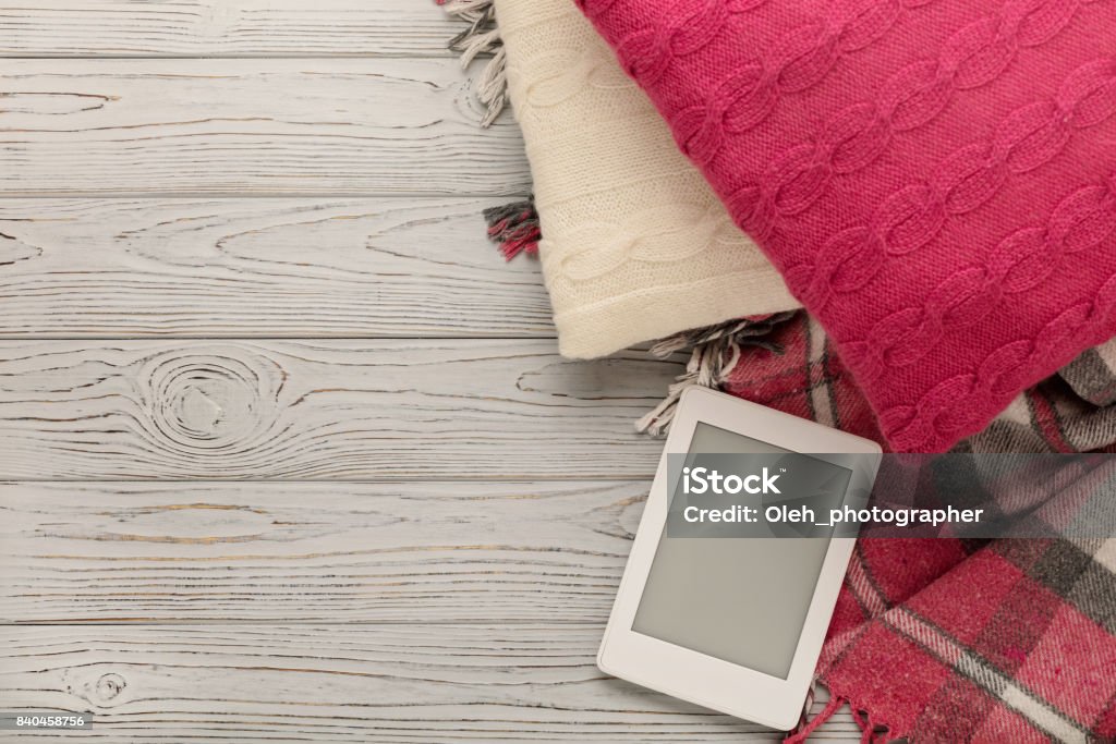 Tricot de coussins, plaid et eBook sur un fond en bois clair. - Photo de Livre électronique libre de droits