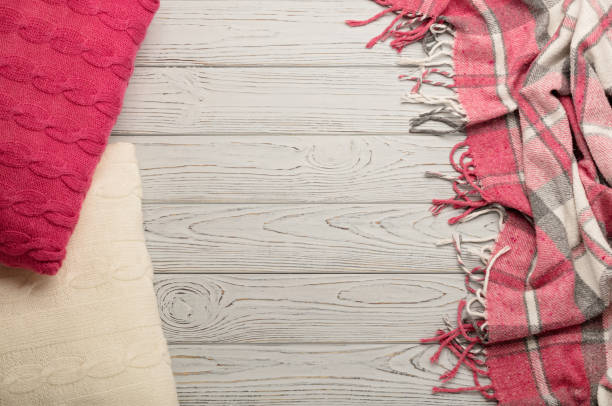 istock Knitted pillows and plaid on a light wooden background. 840458886