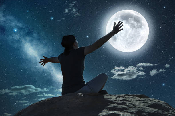 istock woman raising arms in the moonlight 840465734