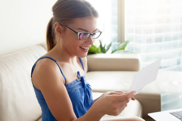 istock Happy woman reading letter on sofa at home 840467446