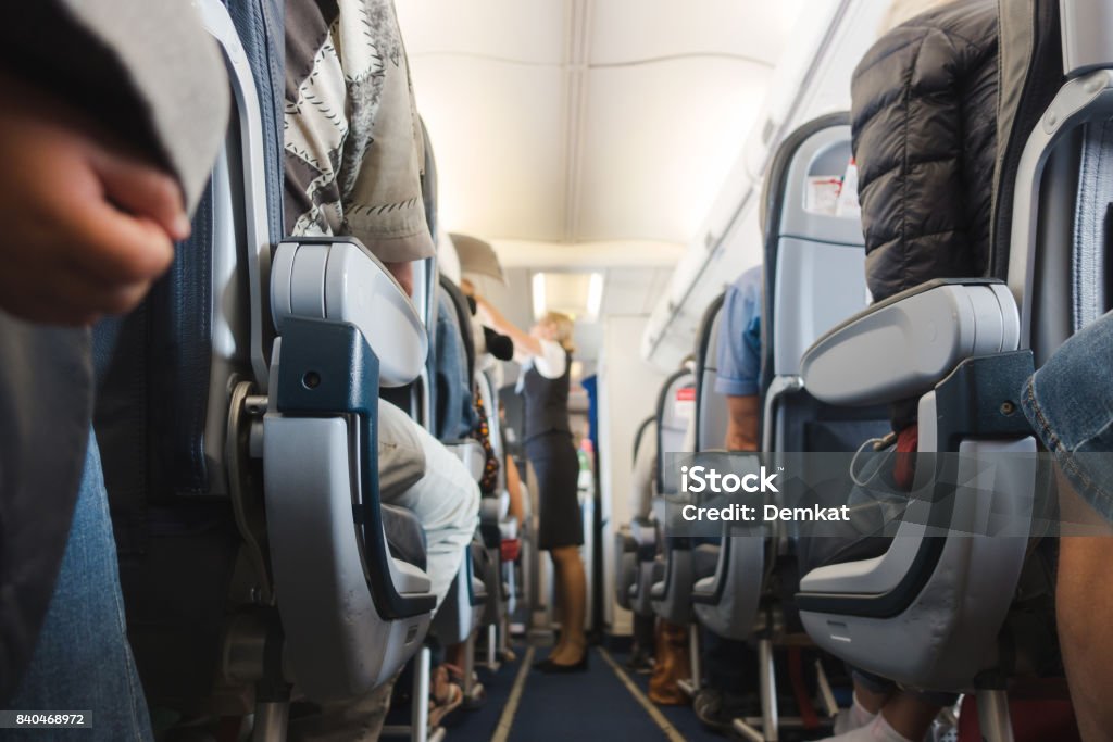 Cabin aisle in airplane Cabin aisle in airplane with rows of seats and passengers. Air Stewardess Stock Photo