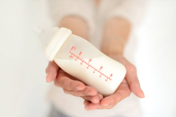 Woman hand holding a baby bottle of milk Woman hand holding a baby bottle of milk over blurred background breast milk stock pictures, royalty-free photos & images