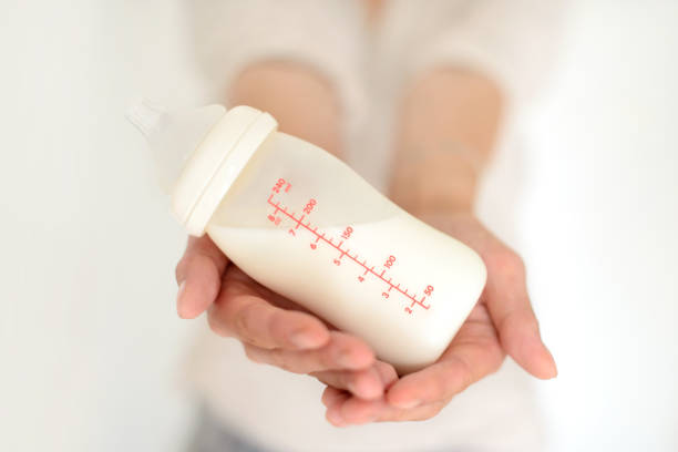 kobieta trzyma butelkę mleka dla niemowląt - mleko z piersi zdjęcia i obrazy z banku zdjęć