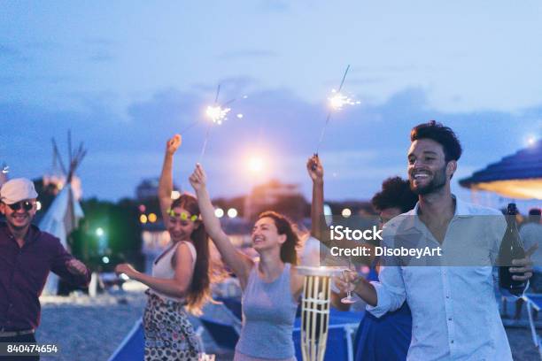 Amici Felici Che Fanno Festa Serale In Spiaggia Allaperto Con Fuochi Dartificio E Champagne Giovani Che Si Divertono Al Bar Chiringuito Con Dj Set Focus Sul Viso Delluomo Giusto Concetto Giovanile Ed Estivo - Fotografie stock e altre immagini di Spiaggia