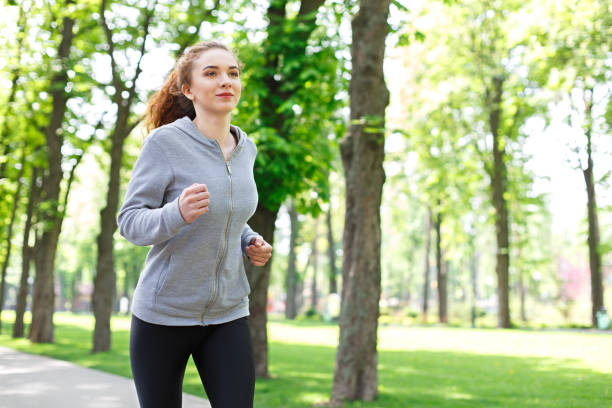 istock Young woman jogging in green park, copy space 840474924