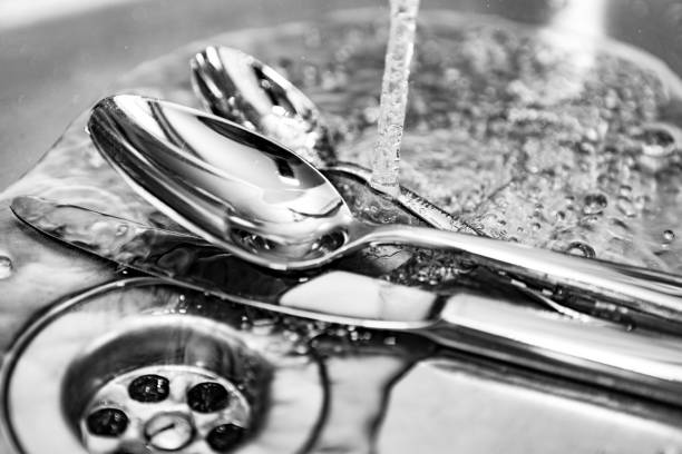 cubiertos en el fregadero de la cocina bajo el chorro de agua - silverware clean wet kitchen utensil fotografías e imágenes de stock