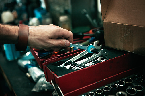 Cropped shot of man’s hand reaching for a tool from his toolbox