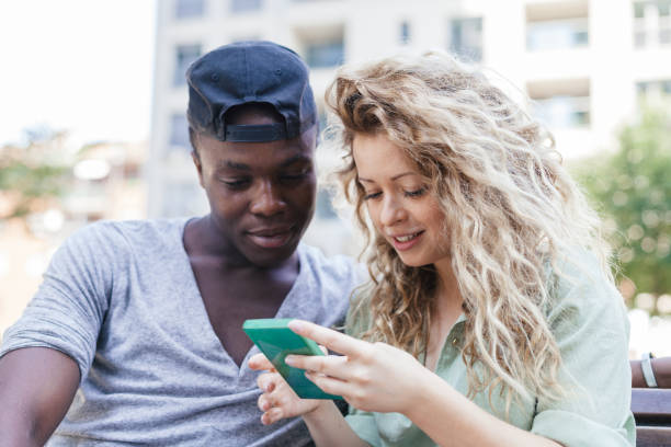istock Loving couple talking using smart-phone on bench in a park during summer 840488672