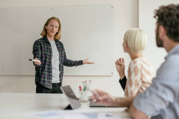istock Young man with curious expression, gesturing with hands in front of whiteboard 840493476