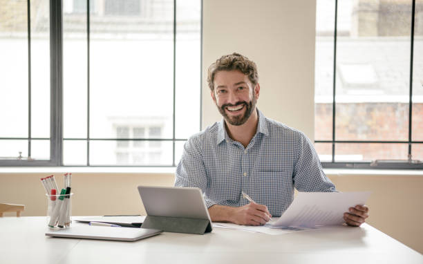 istock Cheerful mature businessman looking at camera and smiling with tablet and document 840493500