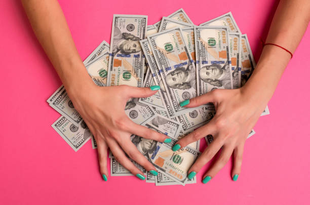 A woman is holding money in her hands. Pink background. Top view copy space stock photo