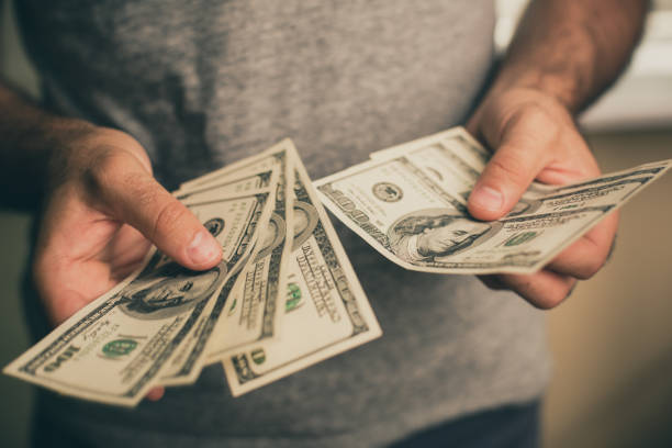 a man holds dollars in his hands - money roll fotos imagens e fotografias de stock