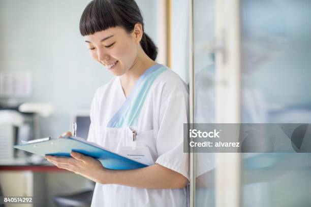 Nurse Writing Medical Report At Hospital Stock Photo - Download Image Now - Japanese Ethnicity, Nurse, Nursing Home