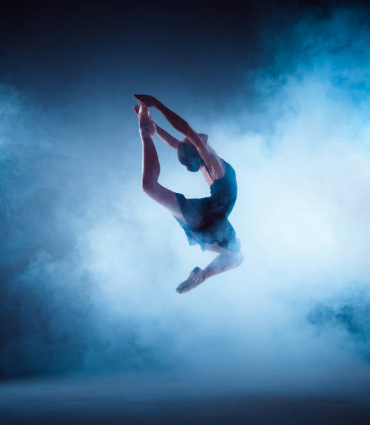 Beautiful young ballet dancer jumping on a lilac background