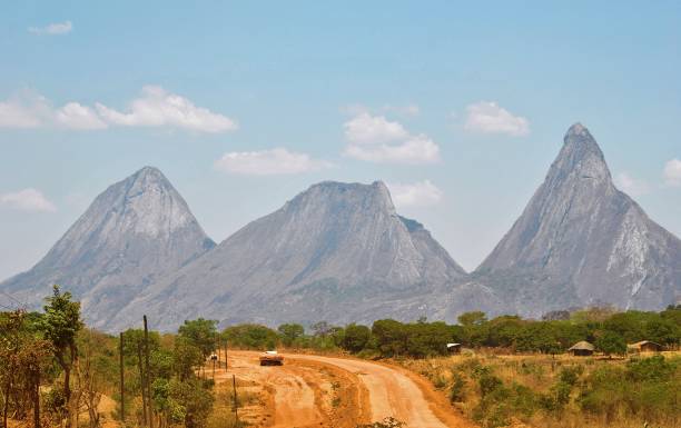 Travels through the wilderness of northern Mozambique A road through the wilderness of Mozambique with the jagged peaks of towering mountains in the backdrop mozambique stock pictures, royalty-free photos & images