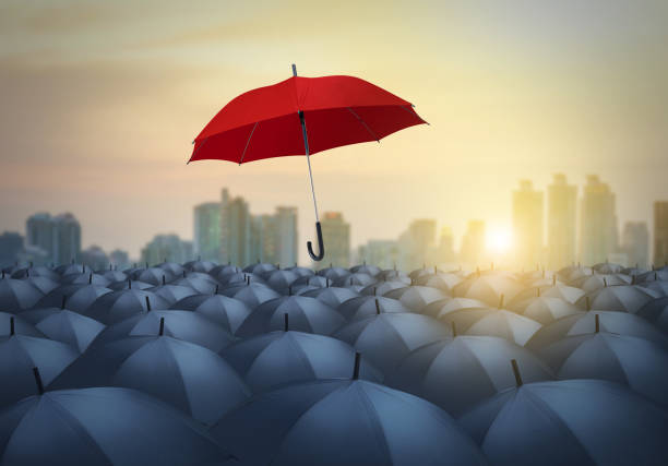 istock unique red umbrella among black umbrellas with city background 840519046