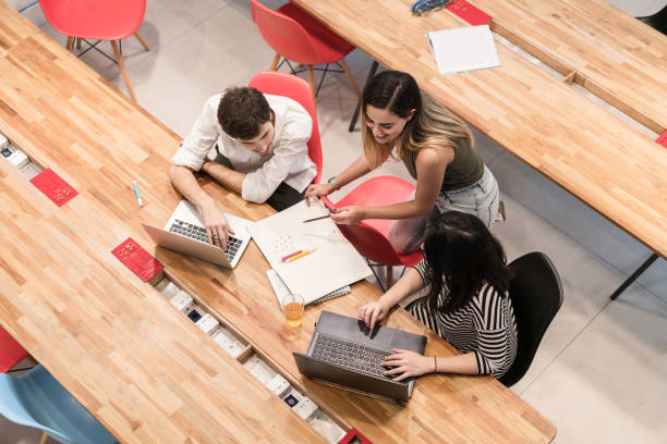 istock High angle view of colleagues using laptops while discussing at desk in creative office 840535110