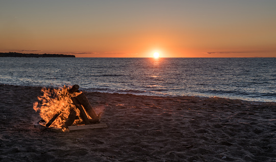 Bonfire on sandy beach with sunset