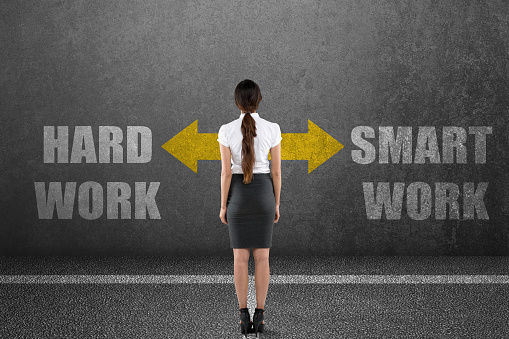 Rear view of businesswoman with hard work or smart work choice on wall