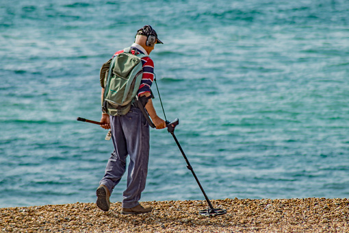 Bournemouth, UK. 22 May 2023. Man using equipment doing metal detecting on Bournemouth beach.
