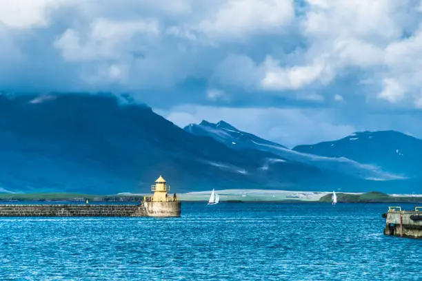 Photo of Entrance to the old harbor of Reykjavik, Iceland, guarded by bright yello lighthouses