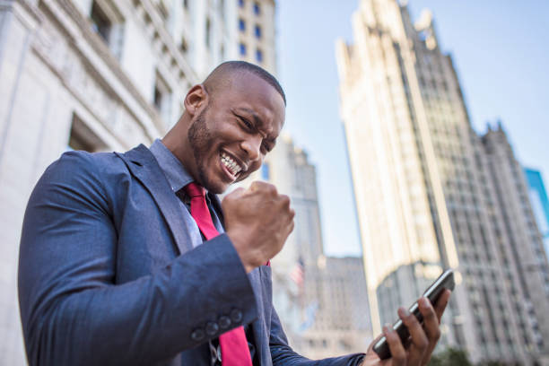 Success businessman Businessman celebrating the good news from his mobile phone in downtown Chicago, USA. chicago illinois photos stock pictures, royalty-free photos & images