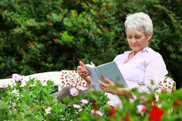 istock Attractive senior woman is reading a book exterior 840582402