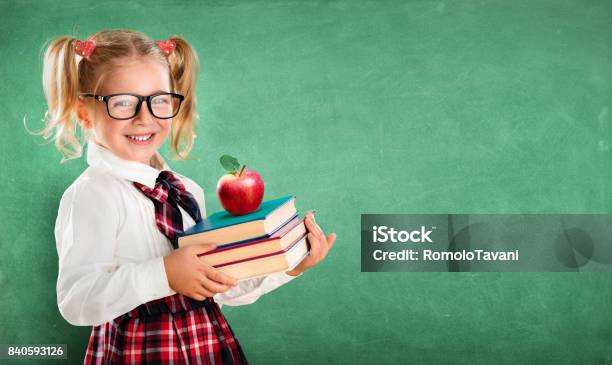 Little Schoolgirl Holding Books And Apple Stock Photo - Download Image Now - Back to School, Elementary Student, Smiling