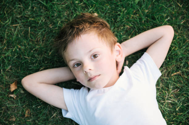 istock cute little kid relaxing lying on green grass 840597338