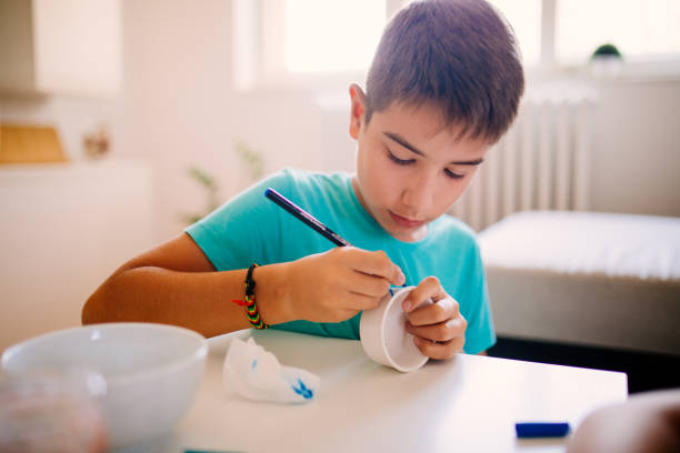 Photo of boy painting ceramic products at home