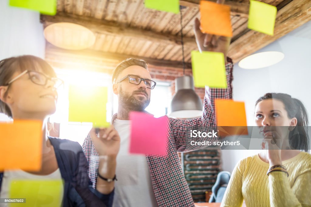 Young creative business people meeting at office. Business people meeting at office and use post it notes to share idea. Brainstorming concept. Sticky note on glass wall. Education Training Class Stock Photo