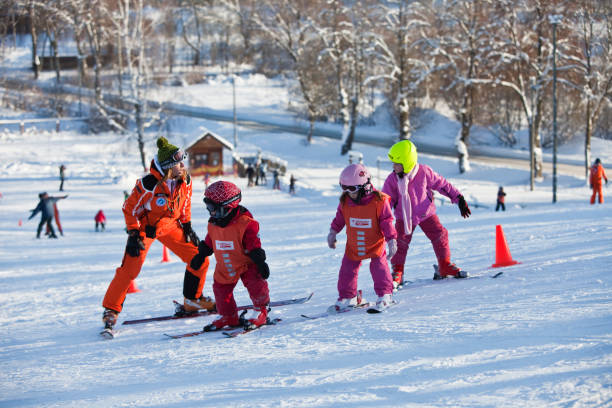 Instructor is teaching kids Sigulda, Latvia - January 10, 2010: An instructor is teaching three kids how to ski on the mountain Kakiskalns track, in Sigulda ski instructor stock pictures, royalty-free photos & images