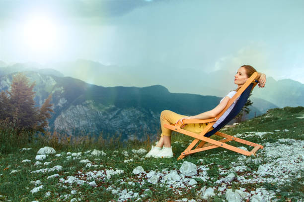 The pretty woman resting and sitting in a chaise lounge at mountain top