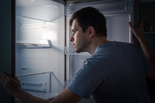 istock Hungry man is looking for food in empty fridge at night. 840623102