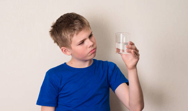 istock Kid observing a half full or half empty glass of water. 840628174