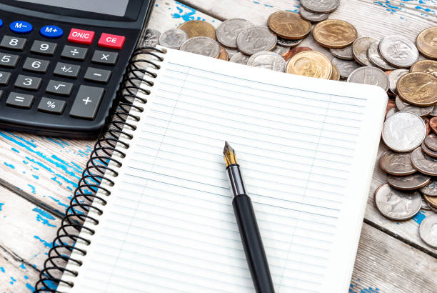 istock Notepad with calculator and coins on the wooden table. Business concept. 840628218