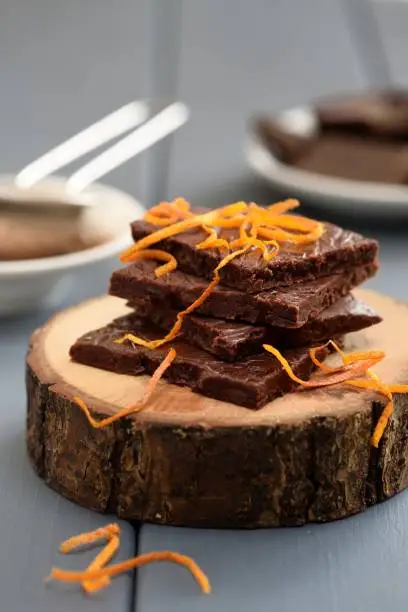 Healthy homemade dark chocolate bars with orange rind on wood slabs vertical
