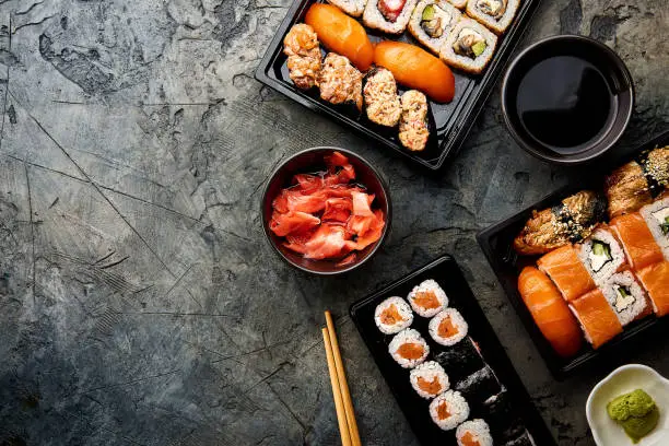 Photo of Variation of sushi and rolls on stone table. Sushi rolls, sashimi set. Top view with copy space.