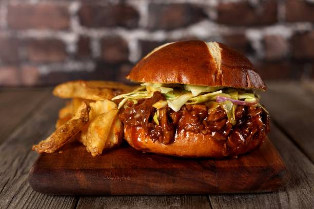 istock Pulled pork burger on pretzel bun with potato wedges 840636110