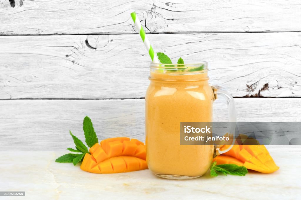 Mango coconut smoothie in a mason jar, on rustic white wood Tropical mango coconut smoothie in a mason jar glass, on a rustic white wood background Smoothie Stock Photo