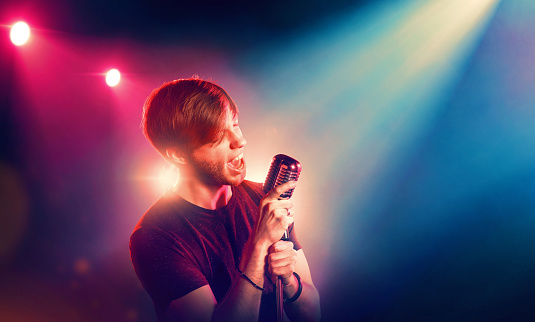 male singer performing on stage with a microphone in his hands