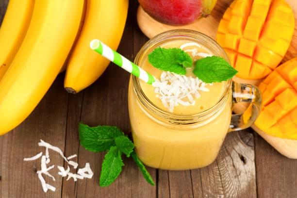 istock Mango, banana, coconut smoothie in a mason jar, overhead on wood 840640868