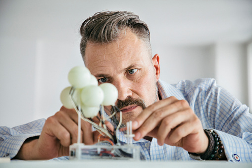 A designer working at his desk, concentrating while carefully building a small mockup.