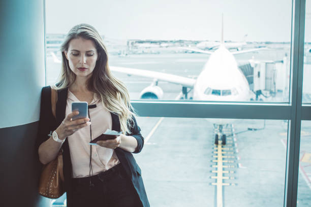 checking her boarding schedule - people traveling business travel waiting airport imagens e fotografias de stock