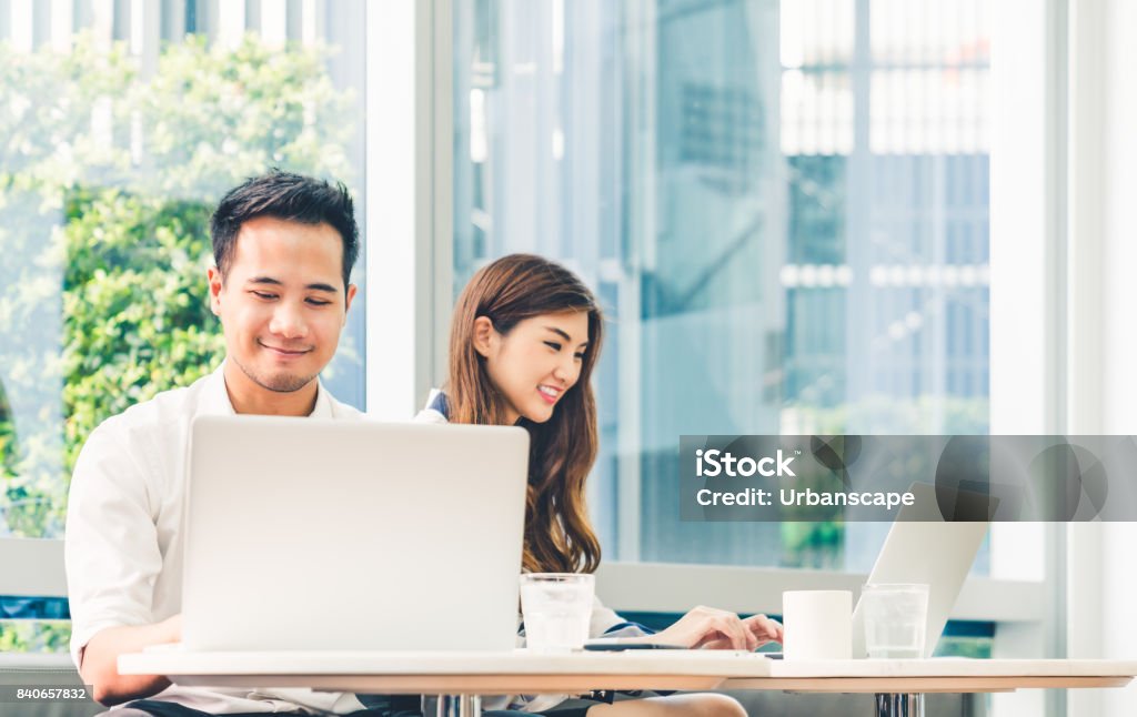 Young Asian couple or college student using laptop computer notebook work together at coffee shop or university campus. Information technology, cafe lifestyle, office meeting, or e-learning concept Laptop Stock Photo