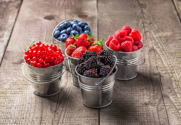 istock Berries colorful mix in tin cans on rustic wooden table 840658984
