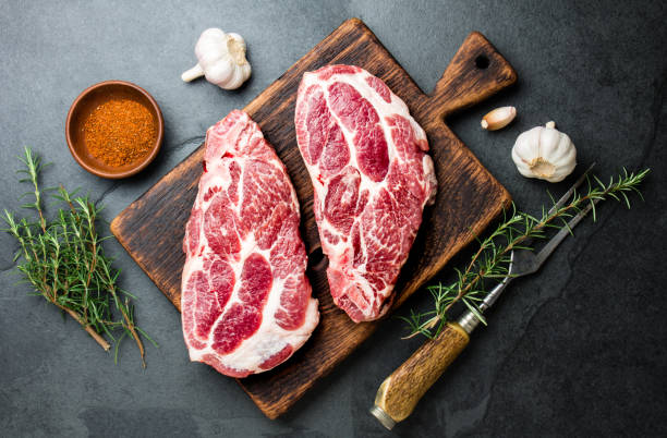 chuleta de chuleta de cerdo cruda para parrilla de barbacoa con hierbas sobre tablero de madera, pizarra de fondo, vista superior - veal rack fotografías e imágenes de stock