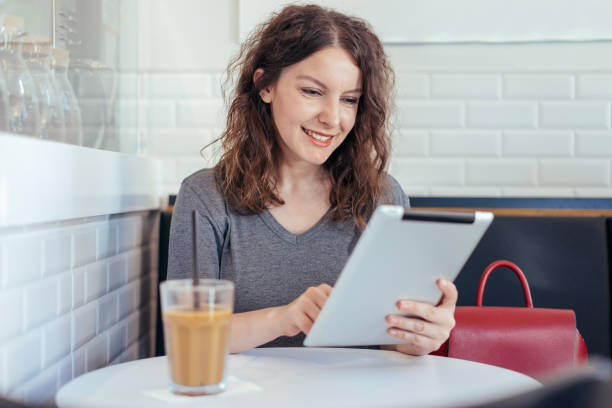 istock Young woman working on her tablet in a coffee shop 840675110