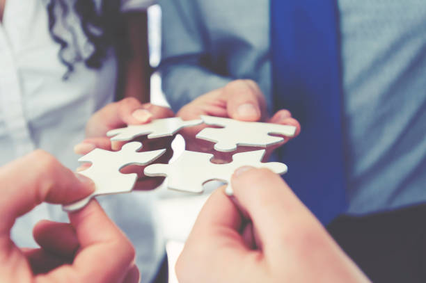 Group of business people holding a jigsaw puzzle pieces. Group of business people holding a jigsaw puzzle pieces. Business solution integration concept. Multi ethnic group. Close up of hands connect the dots photos stock pictures, royalty-free photos & images