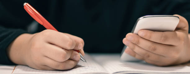 istock Close up of young student with smartphone  writing to notebook. 840682642